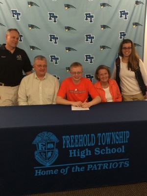Robert signing his letter of intent; he is surrounded by his parents and his coaches