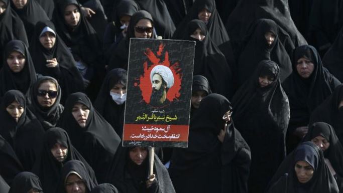 An Iranian woman in Tehran displays a poster showing Sheikh Nimr al-Nimr, the Shi’ite cleric who was executed by Saudi Arabia