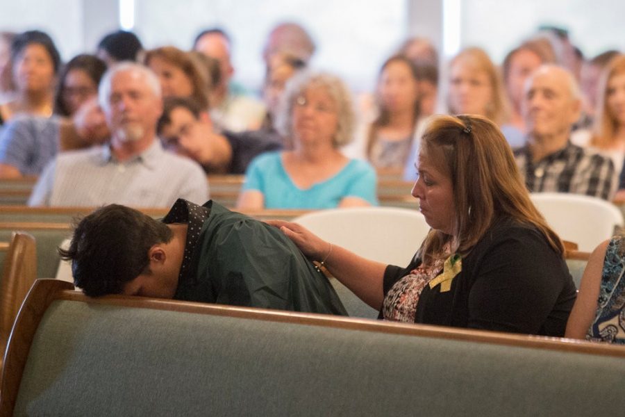 Santa Fe High School seniors sitting with family at a church service in Santa Fe, Tex., following the school shooting. Image courtesy of the New York Times.